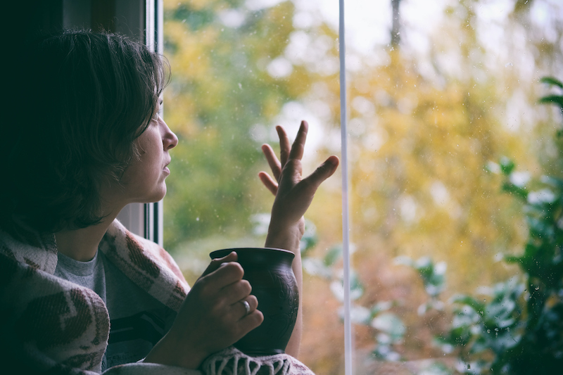 Woman holding tea looking out the window