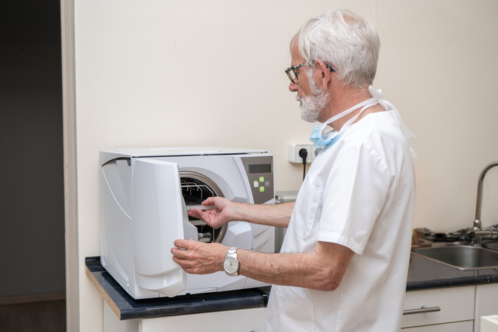 Doctor putting instruments into autoclave for processing